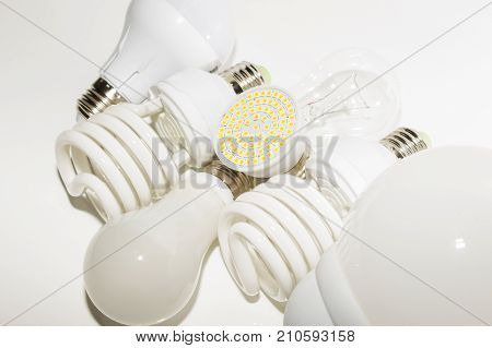 Several different led bulbs and compact fluorescent lamps with the size of the male screw base E27 on a light background