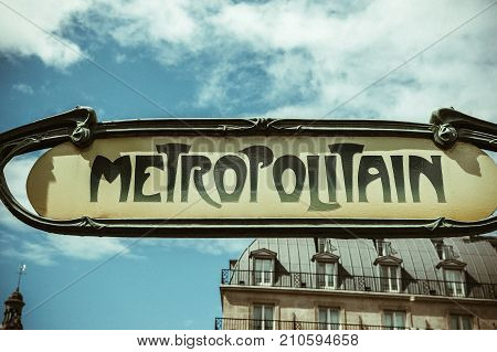 Art nouveau metropolitain sign in Paris France ith traditional French real estate apartment building in the background