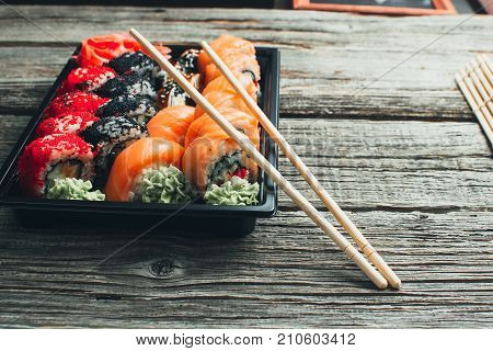 On A Wooden Table In The Black Container Are Nicely Decomposition Sushi