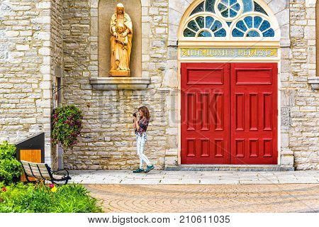 Ile D'Orleans Canada - June 1 2017: Sainte-Famille church with stone architecture and young woman tourist taking pictures