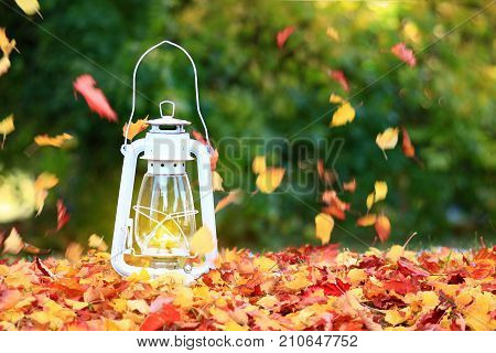 Autumn leaves blowing in the wind across a burning lantern tren