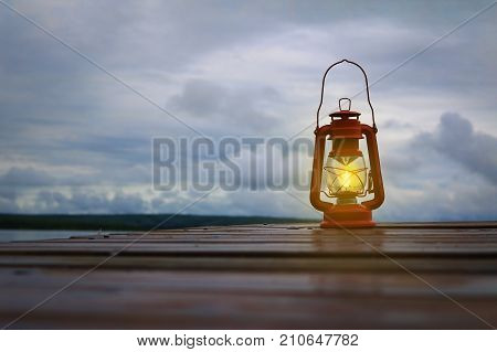 Burning lantern on a dock at a lake in the twighlight
