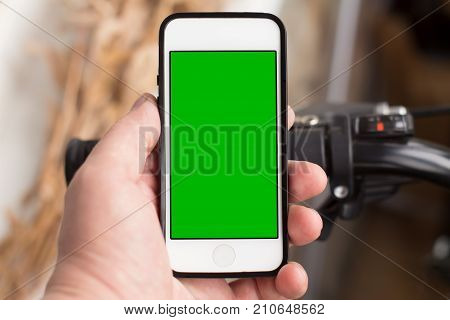 Man's hand use smartphone while he stands near by the road with bicycle. Green screen