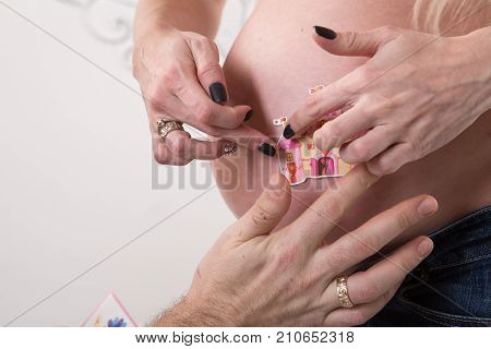 Beautiful pregnant couple in love on the background. Hands of husband on the tummy of his pregnant wife. Young man tenderly stroked pregnant belly of his wife. Husband kissing pregnant belly.