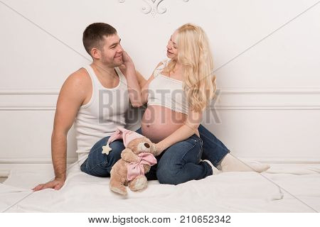 Beautiful pregnant couple in love on the background. Hands of husband on the tummy of his pregnant wife. Young man tenderly stroked pregnant belly of his wife. Husband kissing pregnant belly.