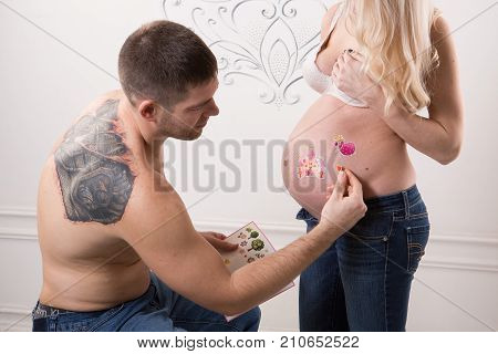 Beautiful pregnant couple in love on the background. Hands of husband on the tummy of his pregnant wife. Young man tenderly stroked pregnant belly of his wife. Husband kissing pregnant belly.