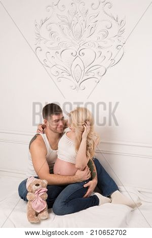 Beautiful pregnant couple in love on the background. Hands of husband on the tummy of his pregnant wife. Young man tenderly stroked pregnant belly of his wife. Husband kissing pregnant belly.