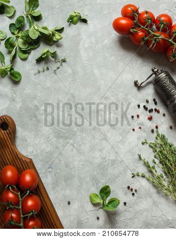 Corn salad in big wooden bowl . Tomatoes, corn salad, spices in a mill and thyme on grey background. Vegetables background