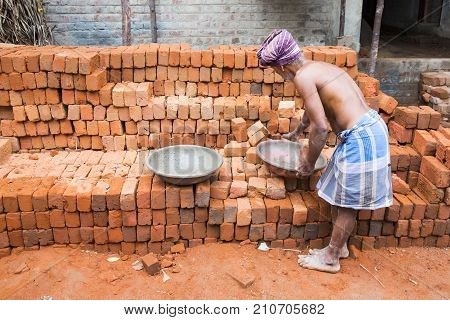 PONDICHERY PUDUCHERY INDIA - September 02 2017. An unidentified indian man puts bricks in a plate for the house construction. Concept of manual labor very hard.