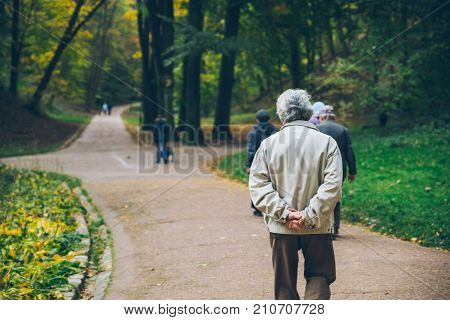 old man walking by autumn park alone