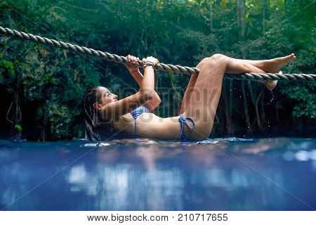 Girl playing with rope in Cenote sinkhole in  Riviera Maya at mayan Mexico