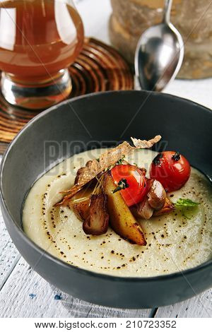 Restaurant Soup Food - Delicious Mushroom Soup with Garlic and Cherry Tomato. Gourmet Restaurant Soup Menu. Mushrooms Soup Garnished with Tea Broth and Garlic Mousse