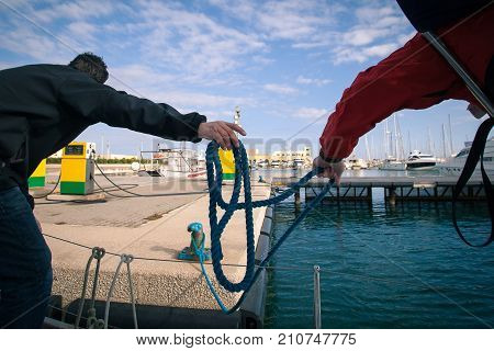 The sailors moored the boat to the dock to the gas station for refueling, then throw the knot in the rope at the pier