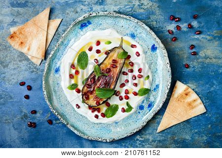 Labneh middle eastern lebanese cream cheese dip with roasted aubergine pomegranate mint and pita. Top view overhead