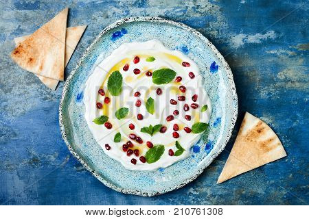 Labneh middle eastern lebanese cream cheese dip with pomegranate mint and pita. Top view overhead