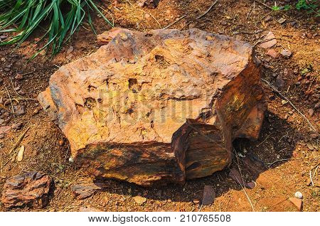 One large piece of iron ore on the ground. Big heavy rock of ore with golden tones. Rock from the Corumba region in Brazil.