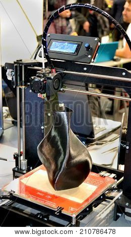 3D printer printing a model in the form of black vase close-up. The concept modern additive technology. The 4ht industrial revolution.