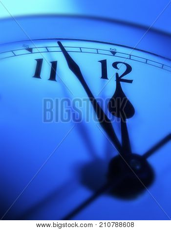 CLOSE UP OF CLOCK FACE WITH HANDS POINTING TOWARDS TWELVE O'CLOCK