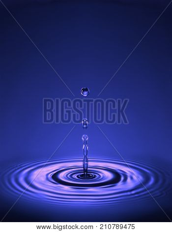 WATER DROPLET MAKING RIPPLES IN COLOURED LIQUID