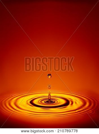 WATER DROPLET MAKING RIPPLES IN COLOURED LIQUID
