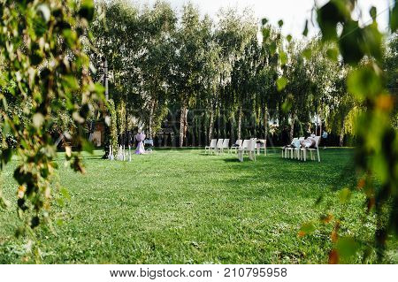 Place for wedding ceremony with white chairs and an arch of living plants