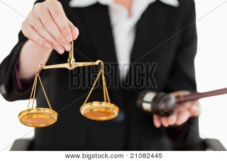 Jeune femme tenant des balances de la justice et un marteau avec l'objectif de la caméra sur la balance contre un brin