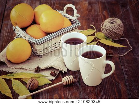tea with lemon, honey, oranges, autumn leaves on woodenbackground