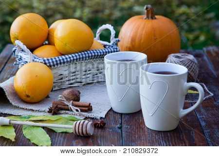 tea with lemon, honey, oranges, autumn leaves on woodenbackground