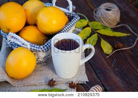 tea with lemon, honey, oranges, autumn leaves on woodenbackground
