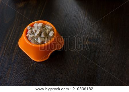 Canned pet food in a orange plastic bowl