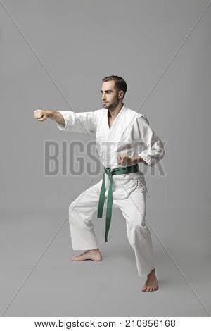 Young man practicing karate on light background