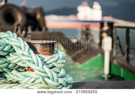 Closeup of old blue frayed boat rope wrapped around rusty cleat