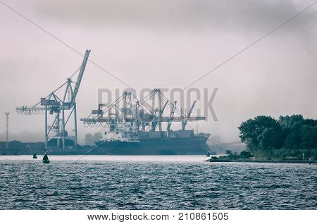 SHIP IN A SEA PORT - Transshipment terminal in the mist