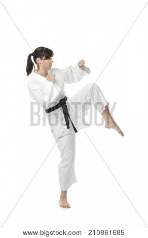 Young woman practicing karate on white background
