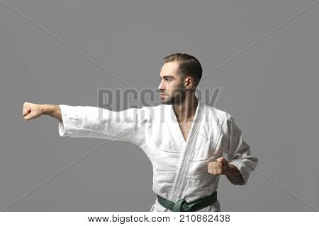 Young man practicing karate on light background
