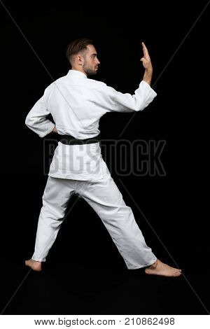 Young man practicing karate on dark background