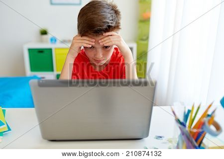 education, cyberbullying and people concept - sad student boy with on laptop computer at home suffering of bullying