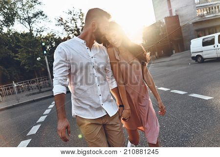 She is his universe. Beautiful young couple holding hands and smiling while walking through the city street