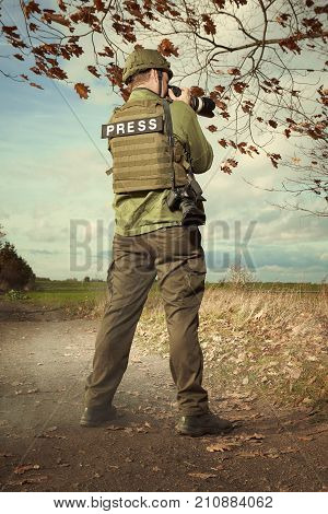Photographer in war conflict field zone taking pictures