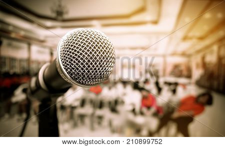 Microphones and computer notebook on front stage in seminar room talking speech in conference hall light with microphone and keynote blur light of meeting room background vintage tone