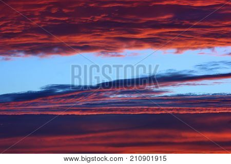 Dramatic sky with rich sunset colors. Incredible alternation of horizontal lines of storm clouds and areas of clear sky.