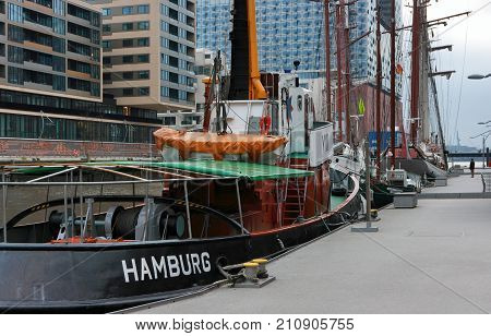 Hamburg, Germany - January 25, 2012. Moored tug and other sailboats in 'HafenCity' modern district of Hamburg.