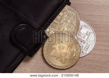 Three Bitcoin in the black leather wallet on the table