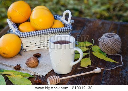 tea with lemon, honey, oranges, autumn leaves on woodenbackground