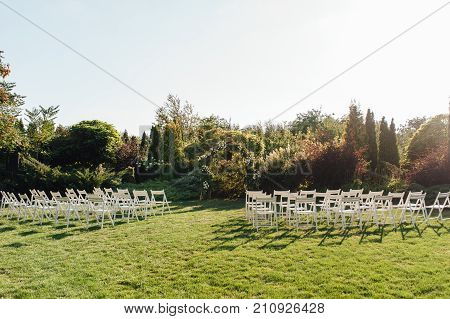 Place for wedding ceremony with white chairs and an arch of living plants