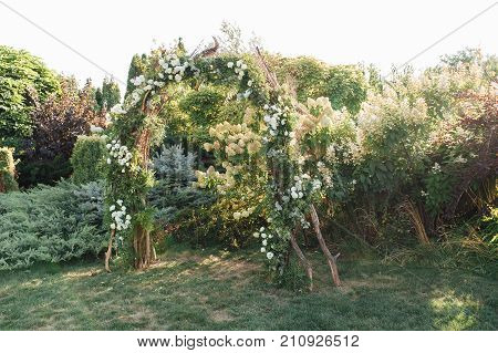 Place for wedding ceremony with white chairs and an arch of living plants