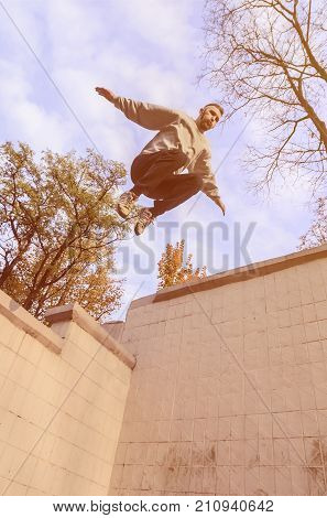 A Young Guy Performs A Jump Through The Space Between The Concrete Parapets. The Athlete Practices P