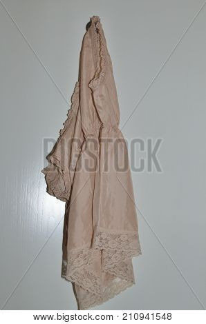 Silk night dress hanged on a wooden white door
