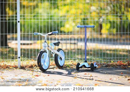 A modern bicycle next to a modern scooter stand on the street in autumn