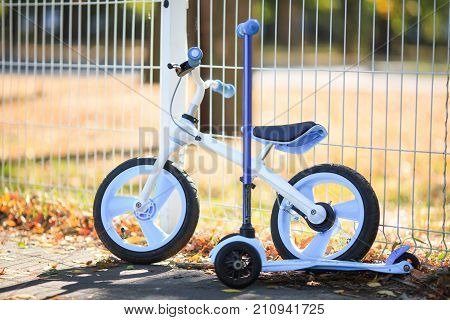 A modern bicycle next to a modern scooter stand on the street in autumn